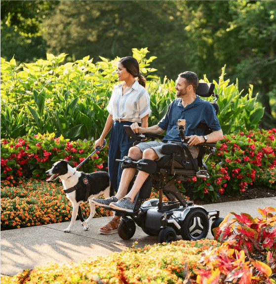 Man On Wheelchair Outside With Woman And Dog