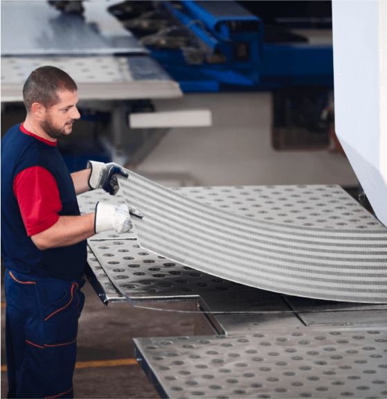 Man Holding Sheet Metal in Factory